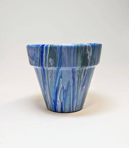Small clay pot with paint poured over it in messy vertical stripes.