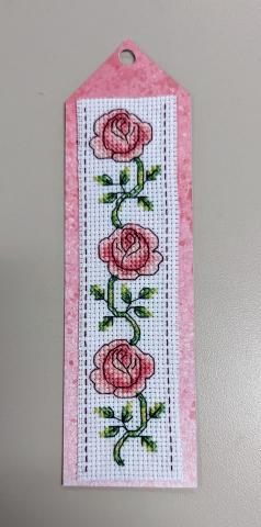 Cross stitch bookmark with 3 pink roses, leaves, & vines on a pink cardstock background.