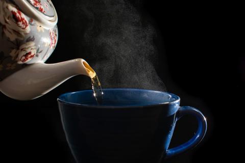 Photo of tea being poured into a tea cup by a teapot