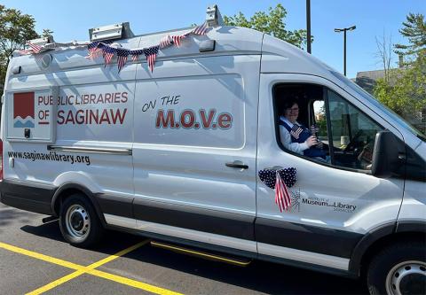 Outreach Library Assistant Claire Skerry waves from the Public Libraries of Saginaw's new Bookmobile