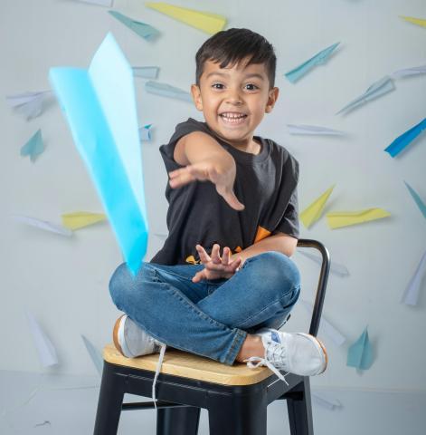 A boy is throwing a paper airplane.