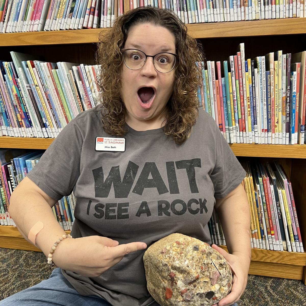 Outreach Library Assistant Beth Lasky points to a giant pudding stone