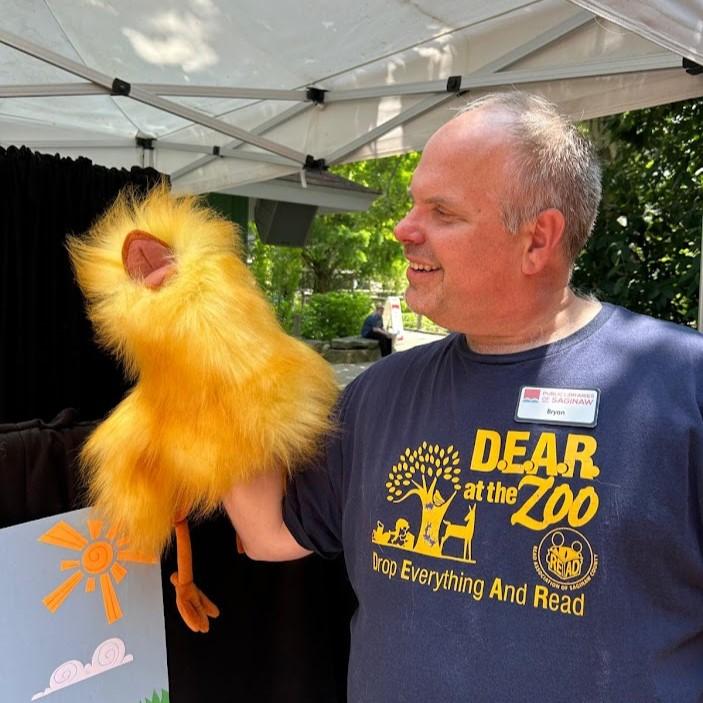 Library Assistant Bryan holds a chick puppet